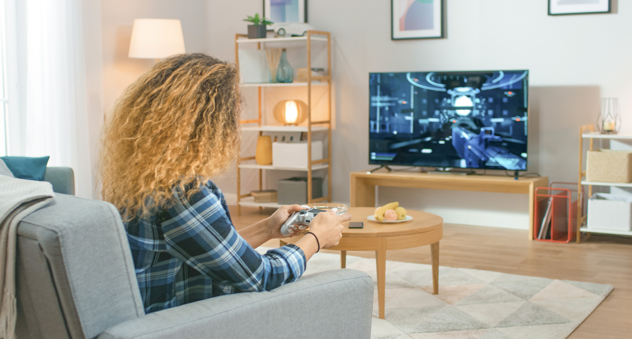 persoon met lang krullend haar in de woonkamer die videogames speelt op een televisie