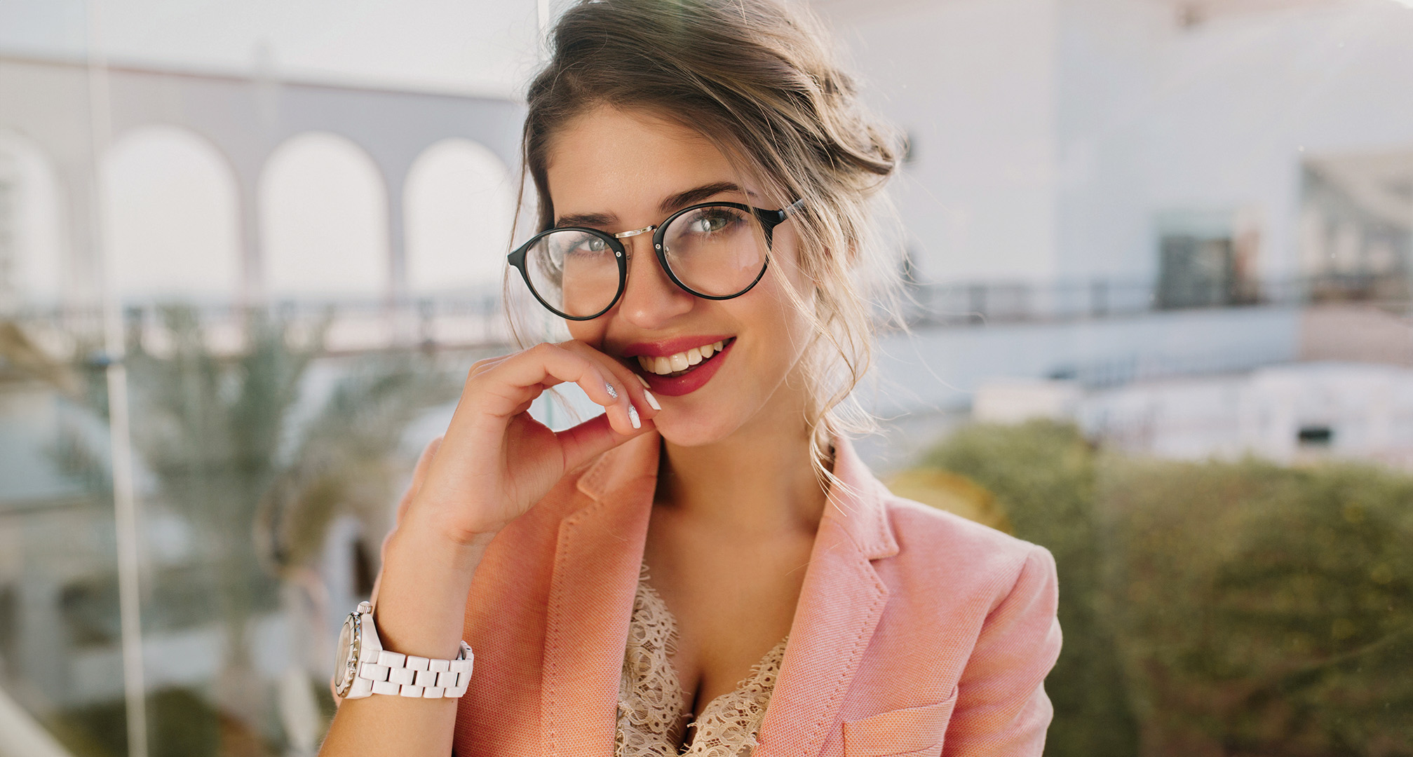 personne portant du rouge à lèvres rouge, des lunettes à monture noire et un blazer rose