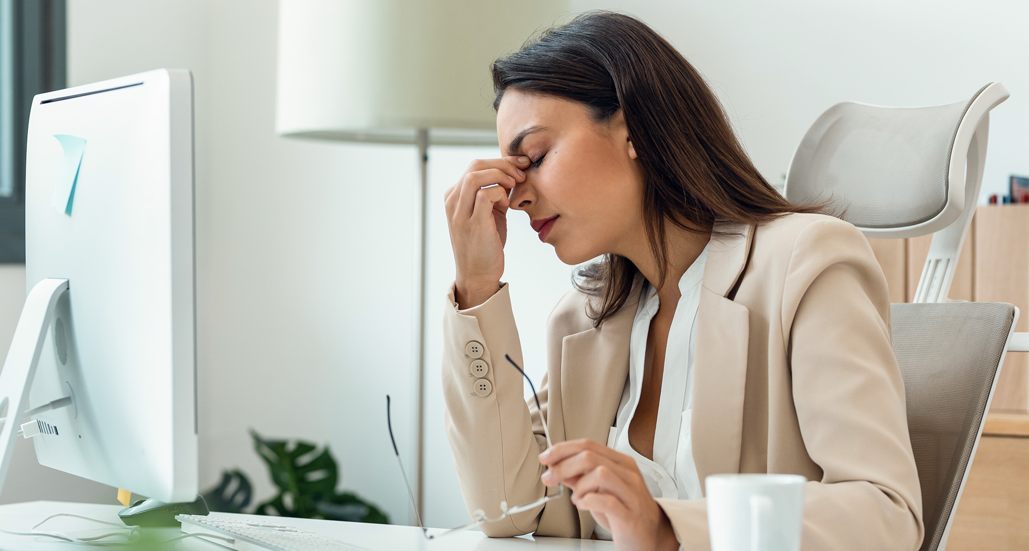 persoon knijpt zijn ogen uit door vermoeide ogen aan bureau met bril