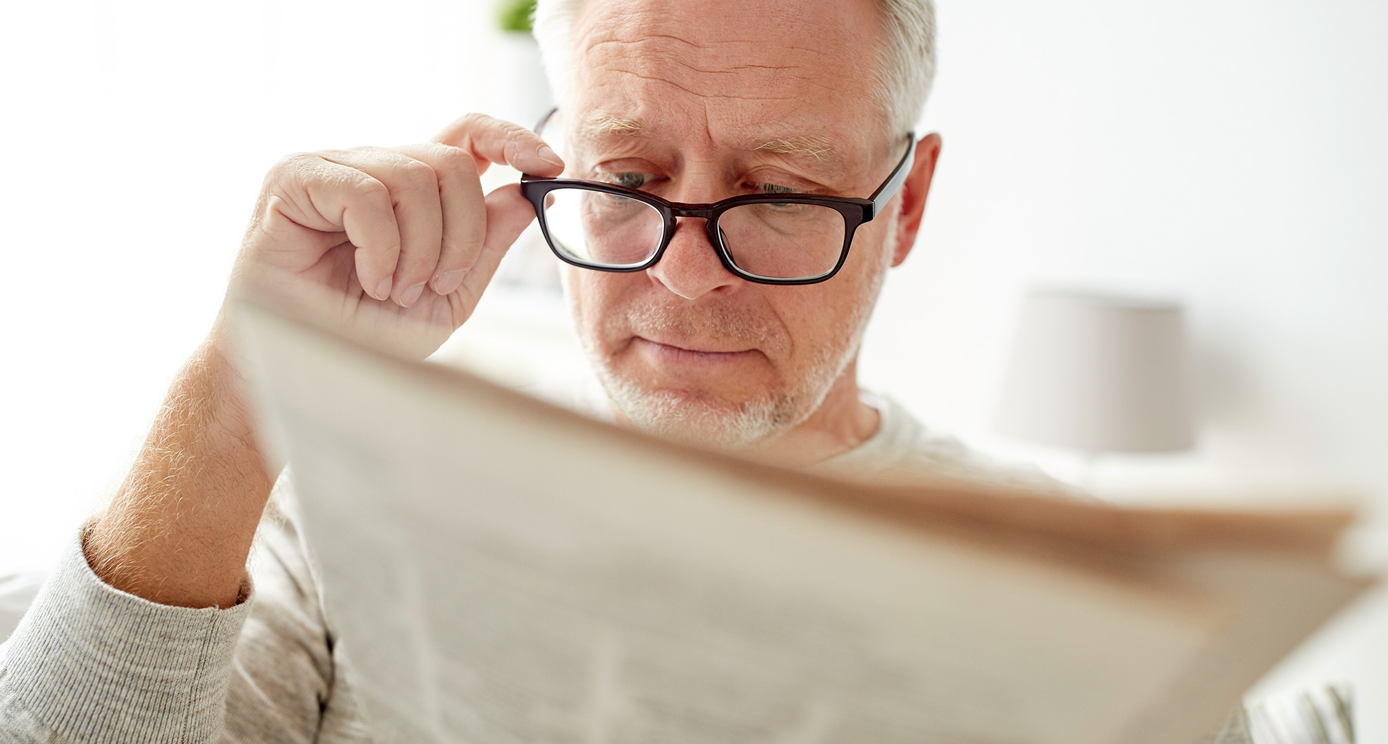 personne lisant et tenant des lunettes au bout du nez